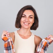 Beautiful woman in top and plaid shirt on gray background with makeup positive confident smile, happy emotions Beautiful woman in top and plaid shirt on gray background with makeup positive confident smile, happy emotions